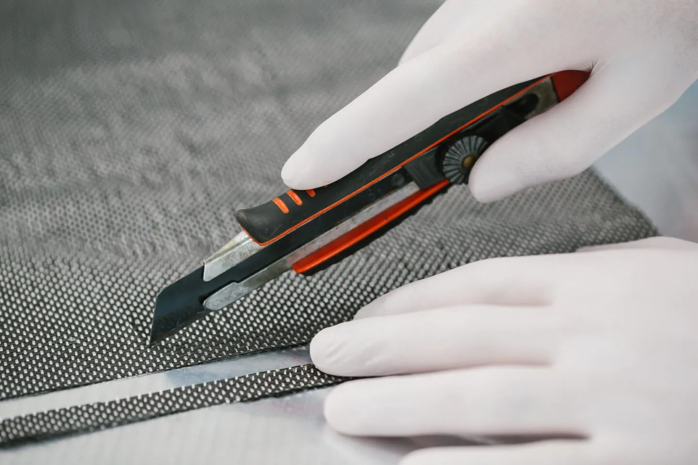 A person in white gloves is skillfully using scissors to cut through material.