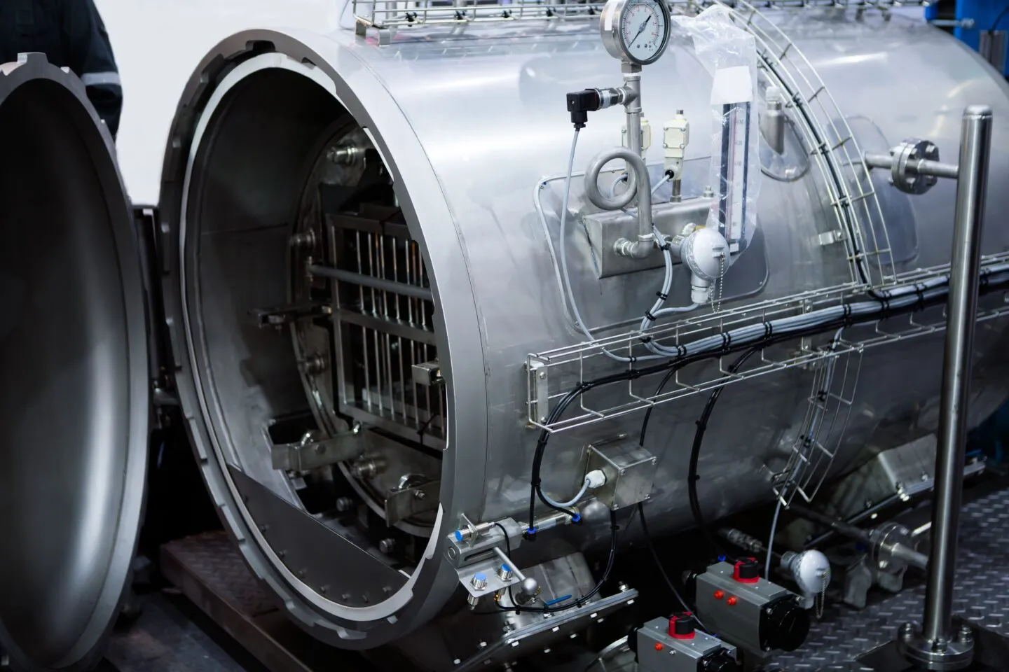 A man stands next to a large metal machine, highlighting its size and presence in an industrial environment.